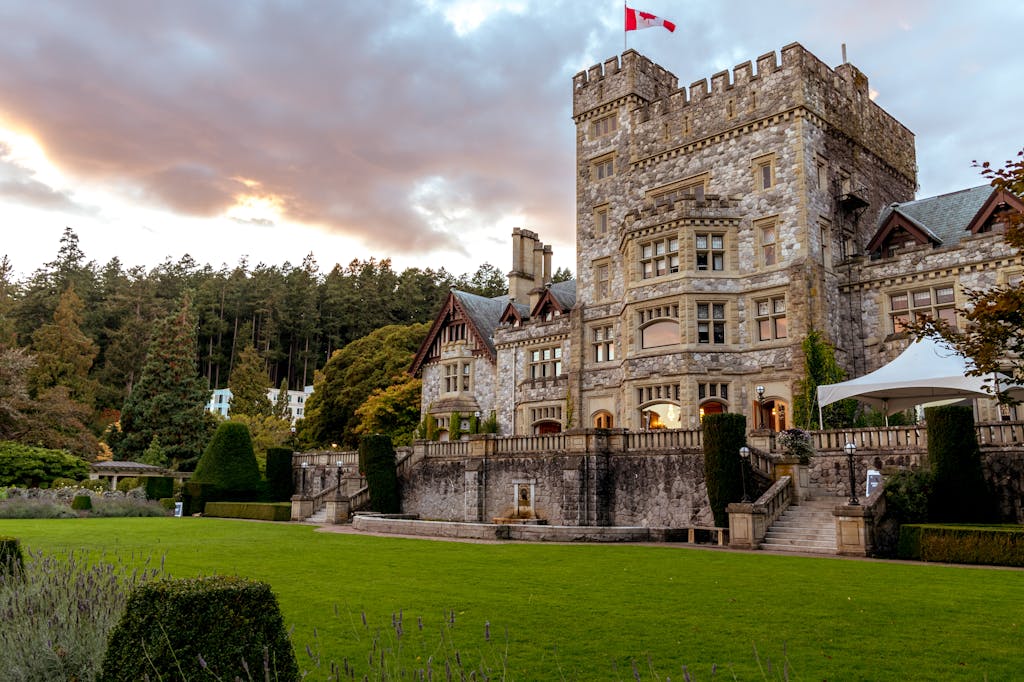 Historic Hatley Castle in Victoria, BC, at sunset, showcasing its stunning architecture and lush gardens.