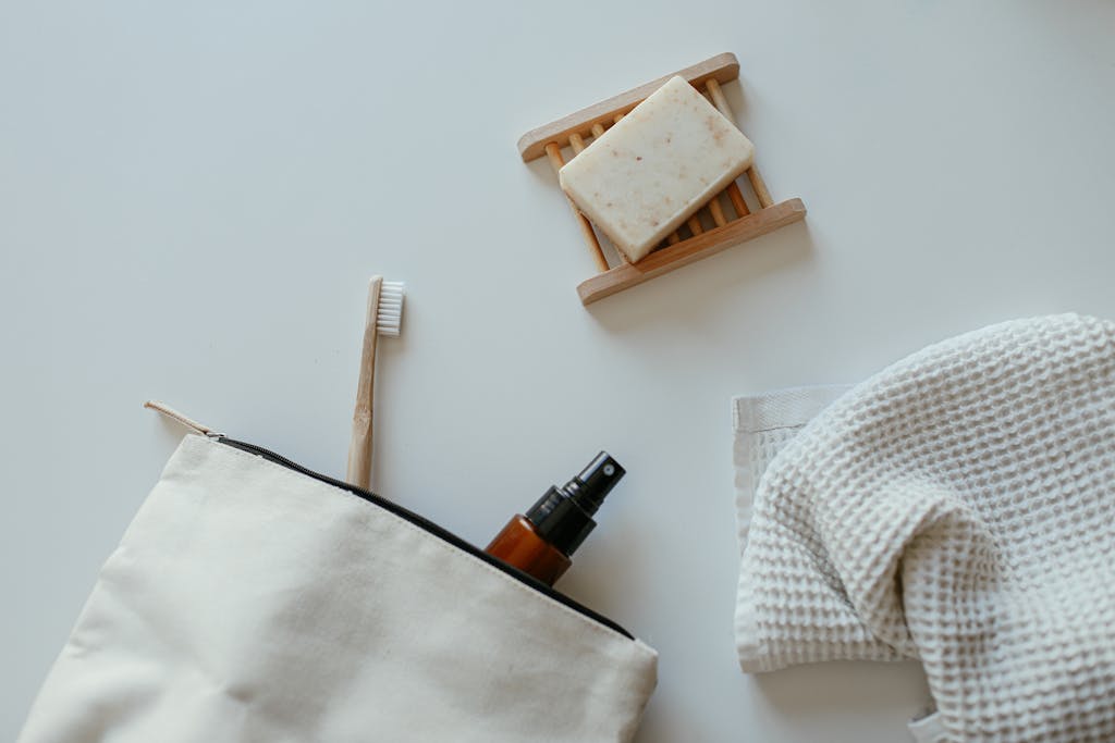A flat lay of eco-friendly bathroom essentials including soap, towel, and spray bottle.