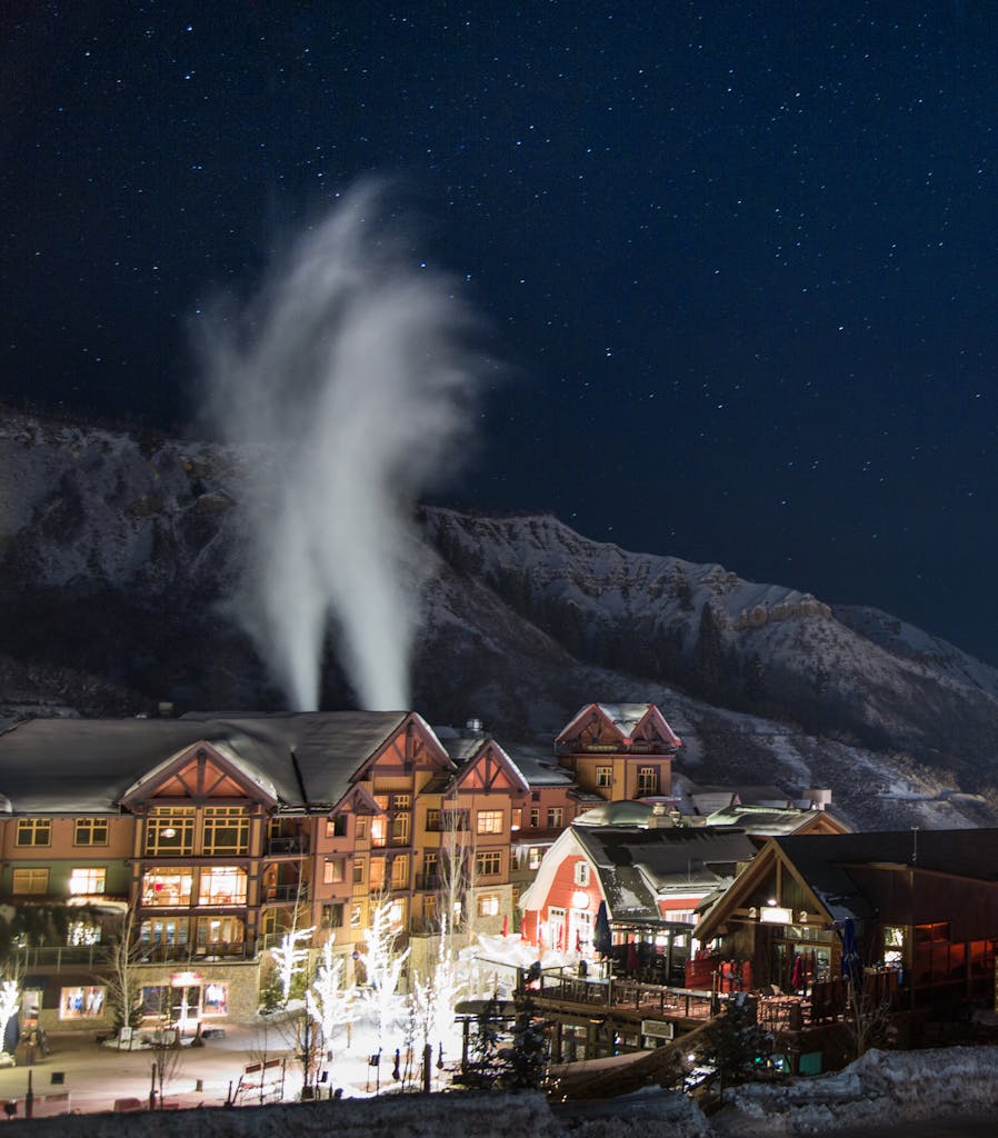 Charming winter night scene in Snowmass Village with snow-covered buildings under a starry sky.